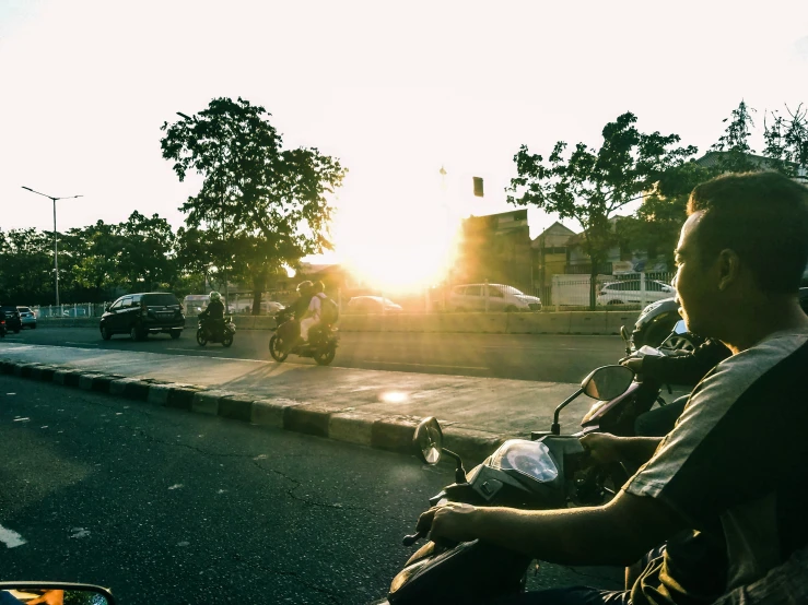 two men riding motorbikes down the street in front of some buildings