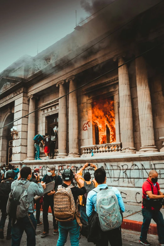 people are standing outside of a building with a fire