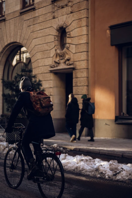 a woman riding on the back of a bike down a snow covered street