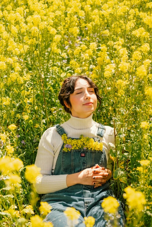 a woman wearing overalls laying in the grass