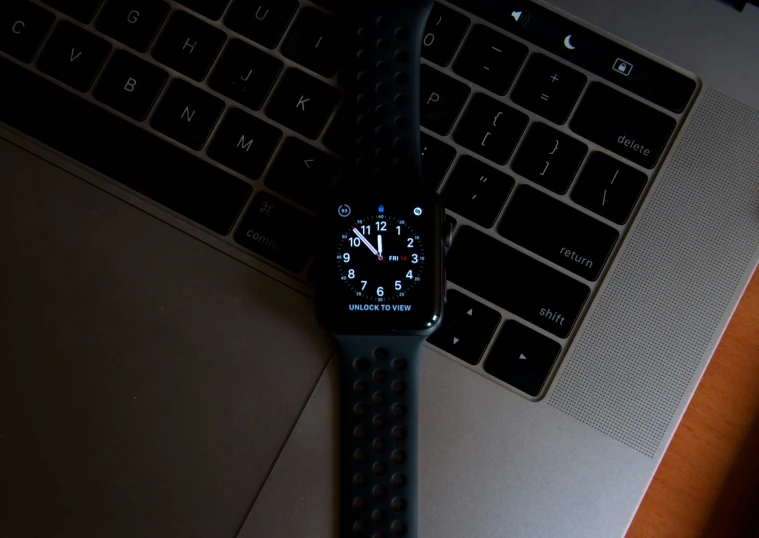 an apple watch next to a laptop on a desk