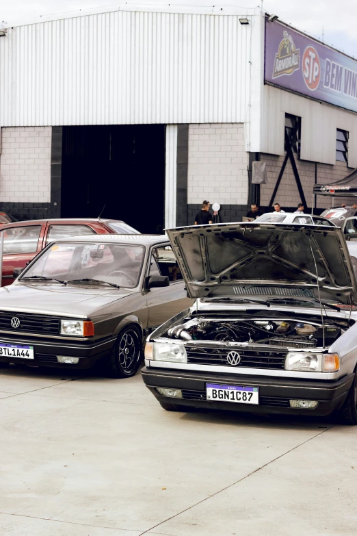 two cars in a parking lot with the hood up