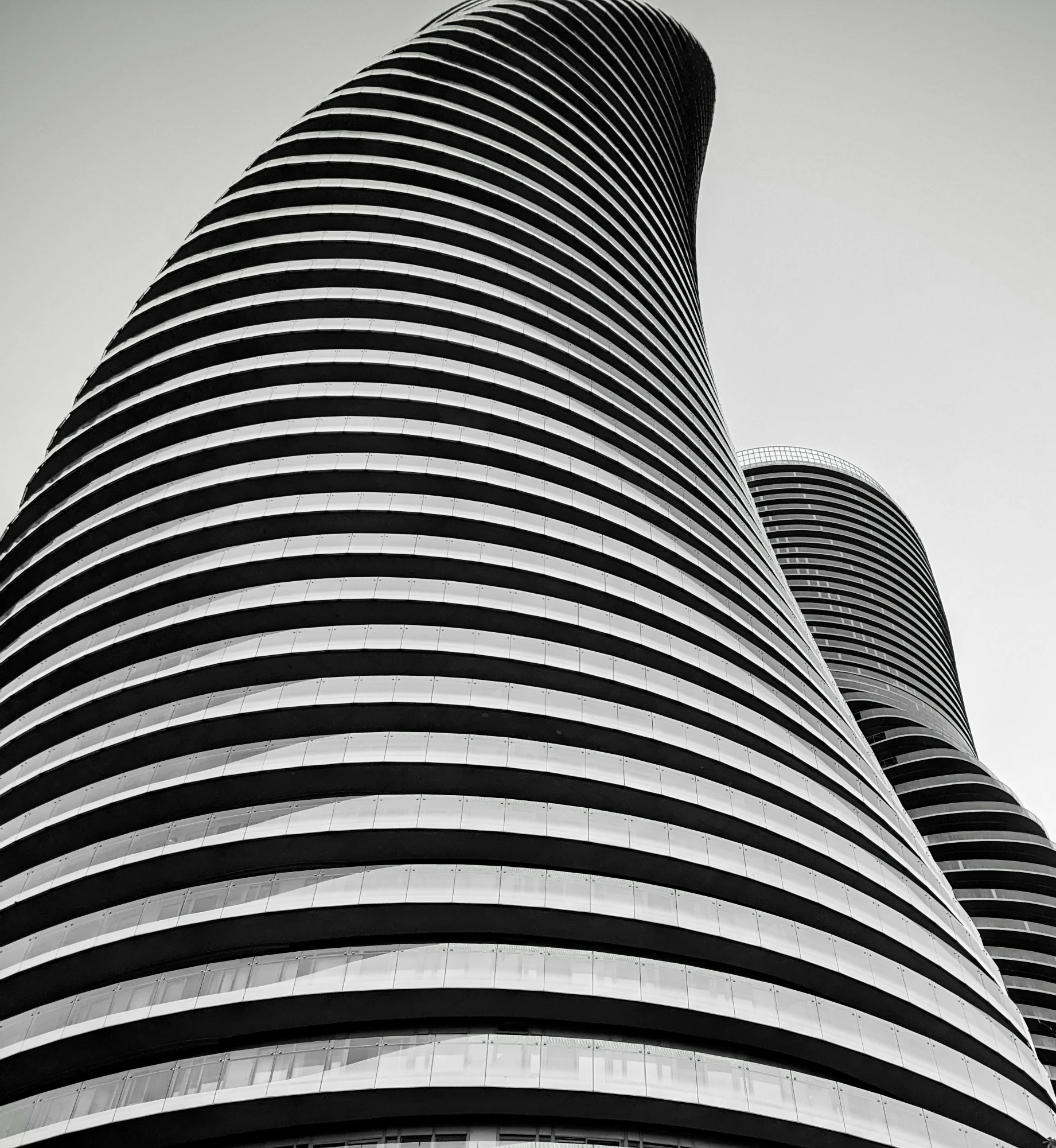 a tall, wavy building with some tall buildings near by