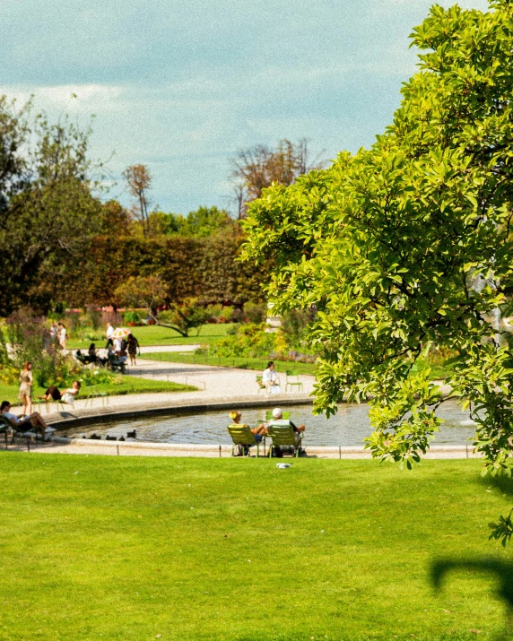 several people are sitting by the water in a park