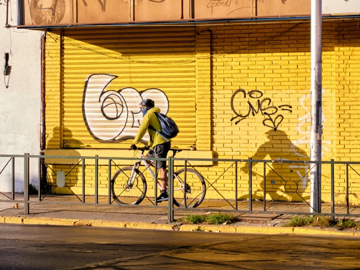 a man riding his bike past a graffiti covered wall