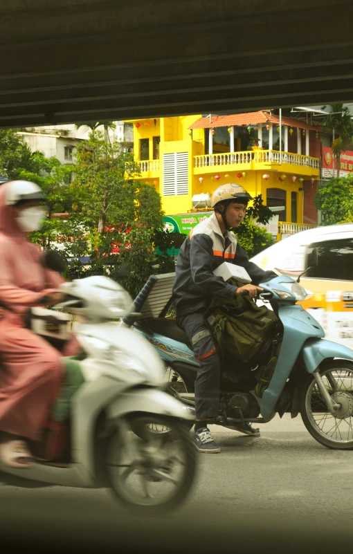 a man on a scooter in front of a yellow building