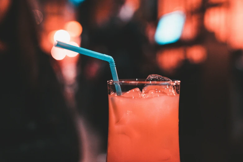 a drink is in a glass next to a bright blue straw