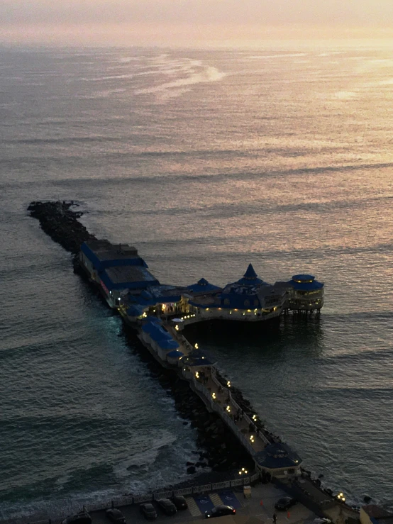 a pier sitting on top of the ocean at sunset