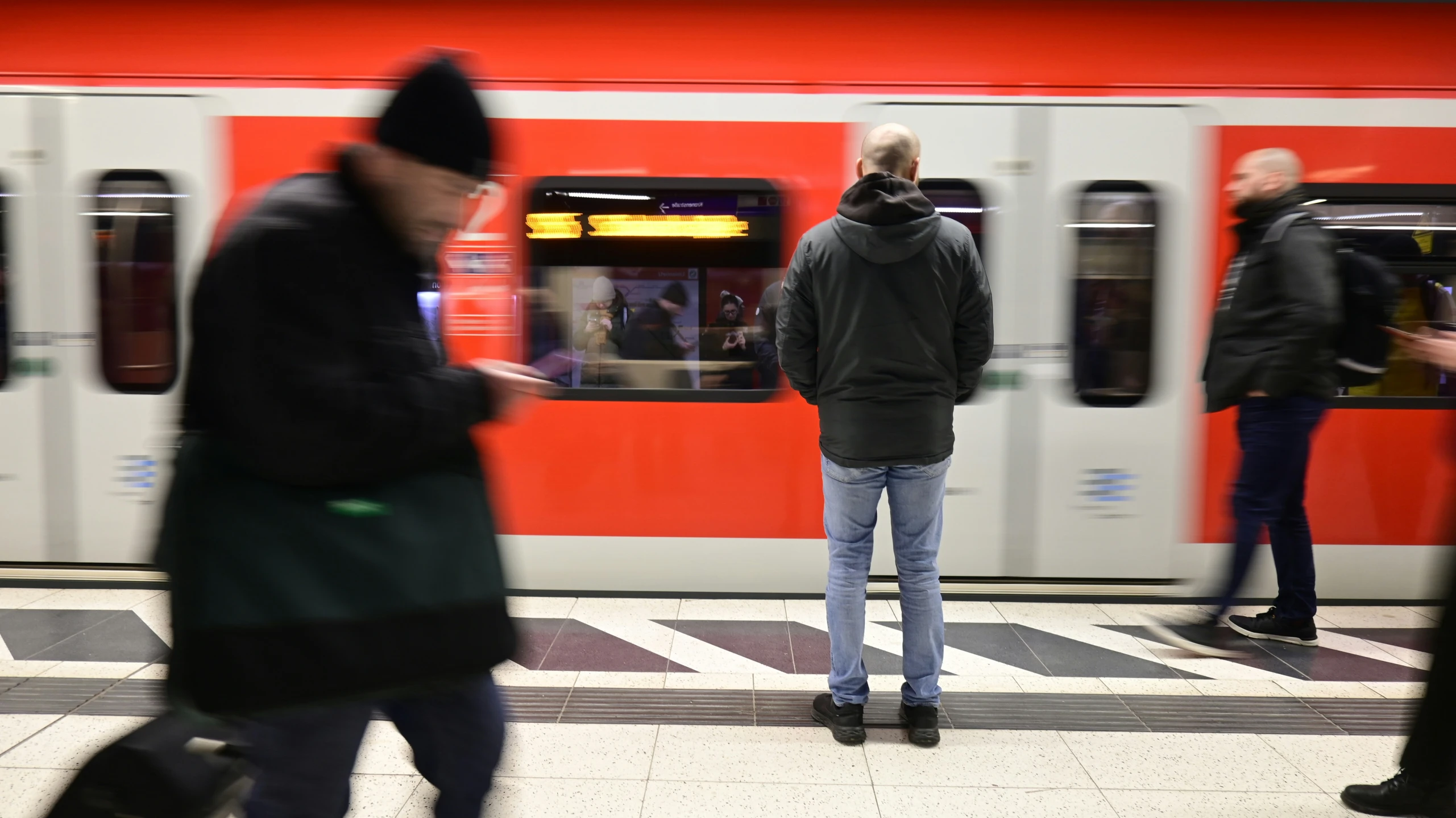 people waiting to board the subway train as it arrives