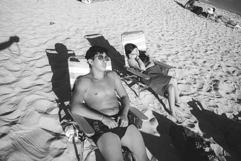 the boys are sunbathing on the beach with their luggage