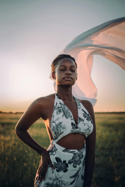 a woman standing in a field with a scarf dd around her