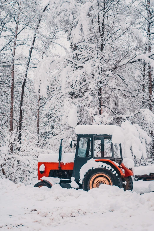 a tractor in the snow with trees in the background