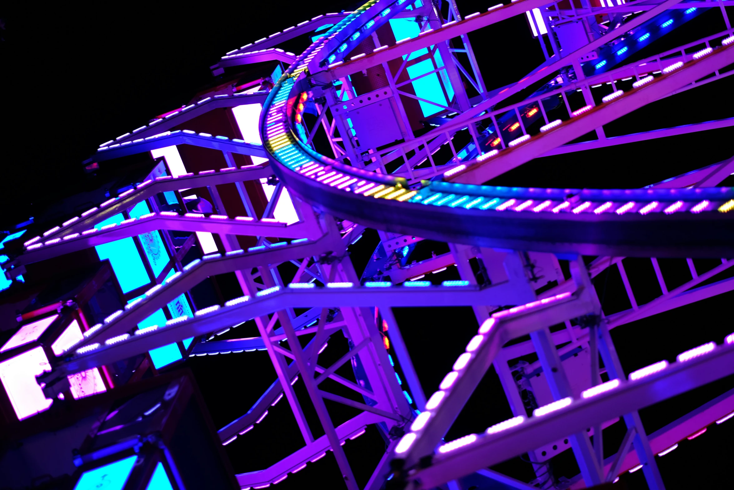 several roller coasters with neon colored lighting