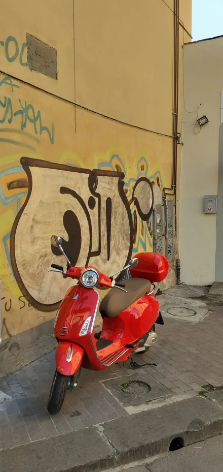 the motorcycle is parked next to the graffiti covered building