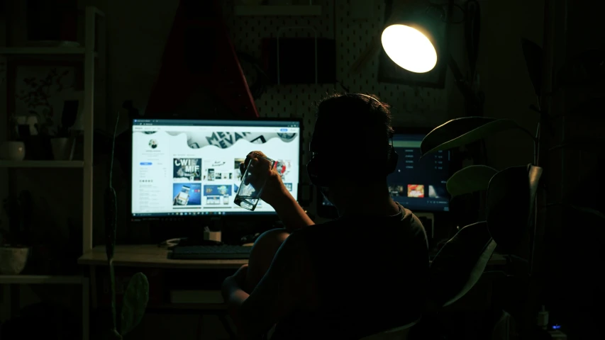 a man in a dark room looking at his computer screen