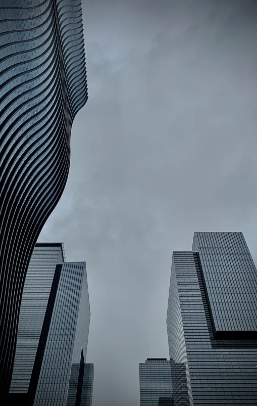 two very tall buildings that have some clouds in the background