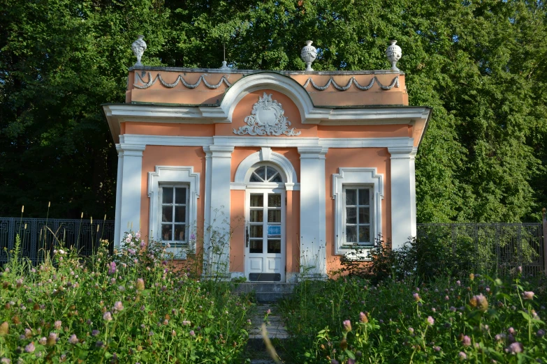 an old, pink - painted small house surrounded by greenery and trees