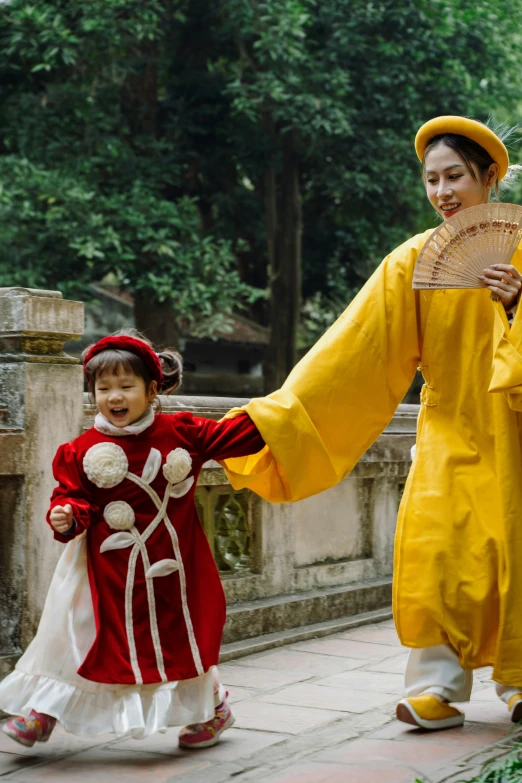 a little girl is walking behind a woman in yellow