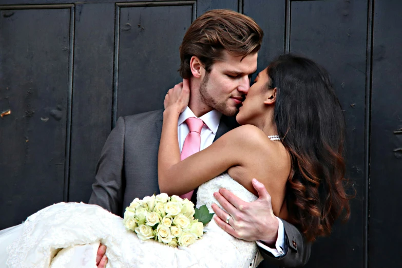 a couple wearing wedding dress in front of a wooden door