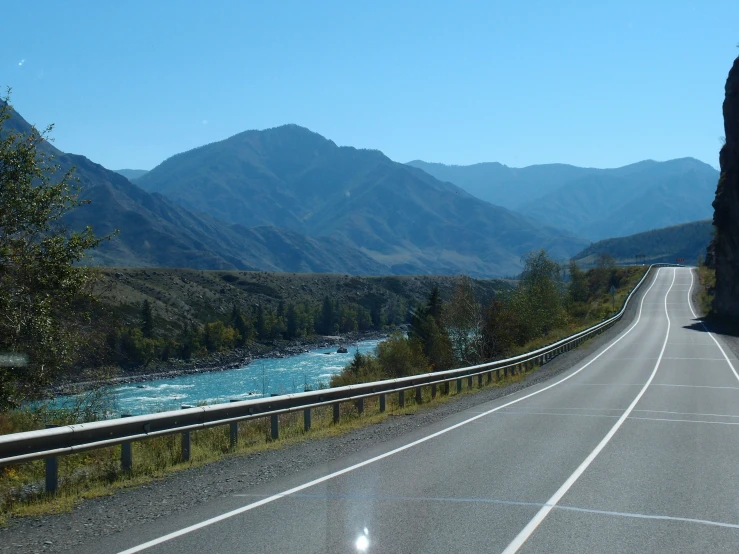 the windshield of a car on the road near a stream and mountains