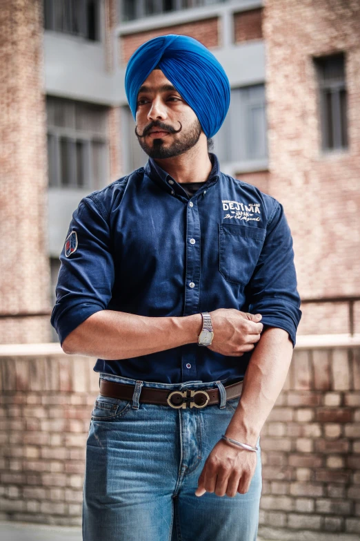 a man in blue turban standing with his arms folded