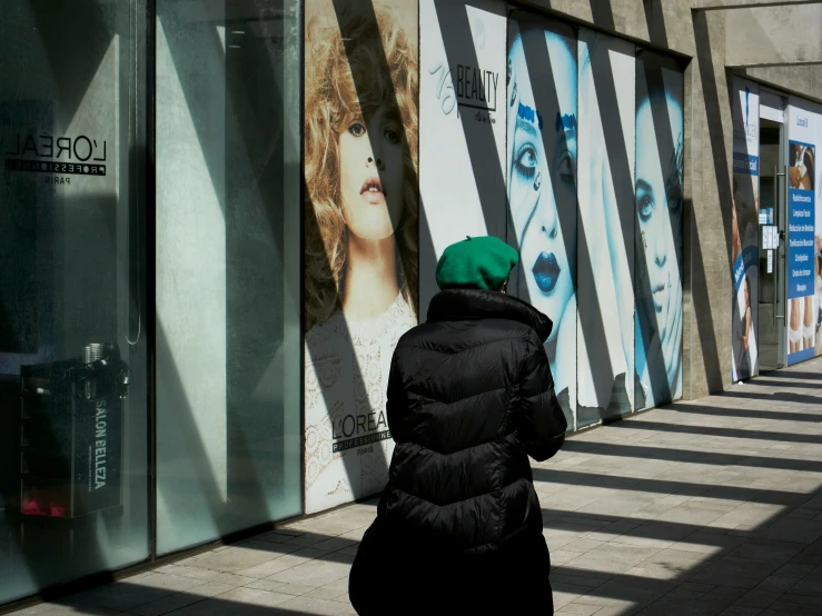 woman in black coat and green hat next to window