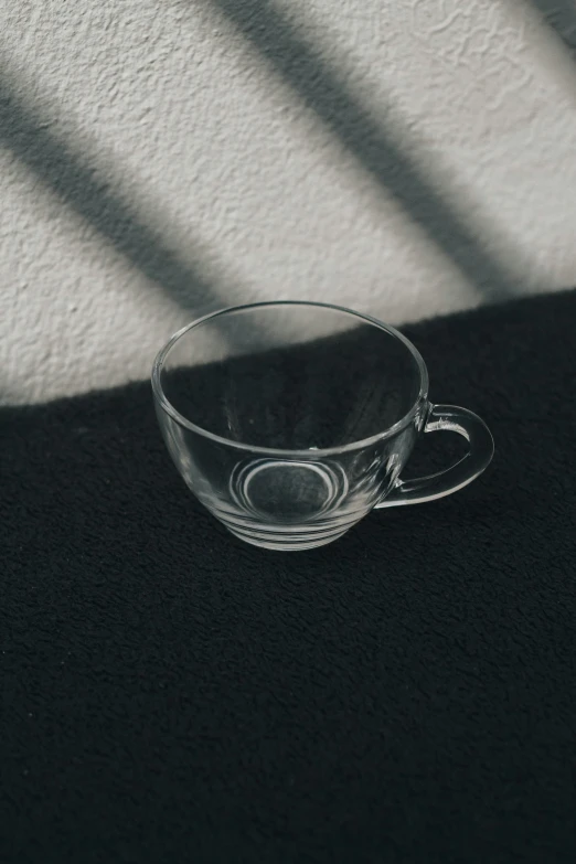 a coffee cup sitting in the shadows on a black surface