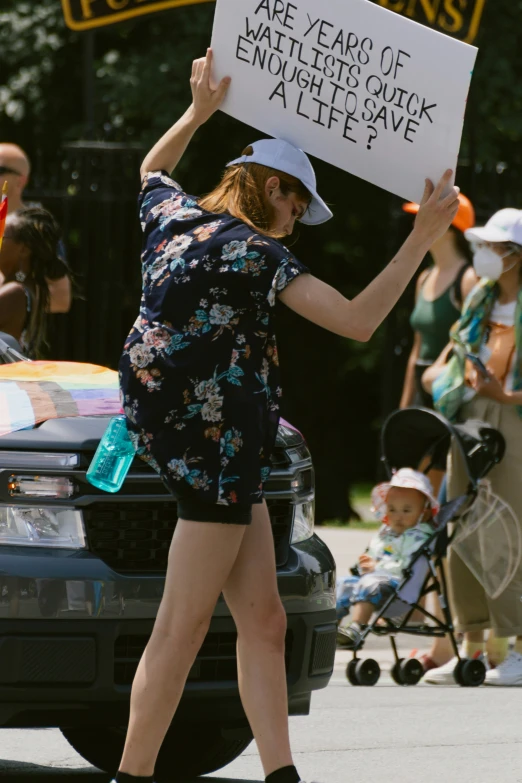 a pregnant woman holding up a sign while walking
