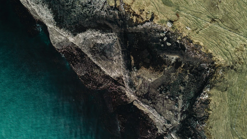 a bird's eye view of a blue body of water next to a rocky cliff
