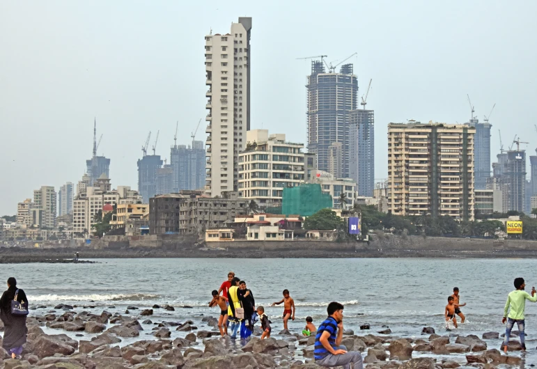 people standing and walking in front of some water with skyscrs