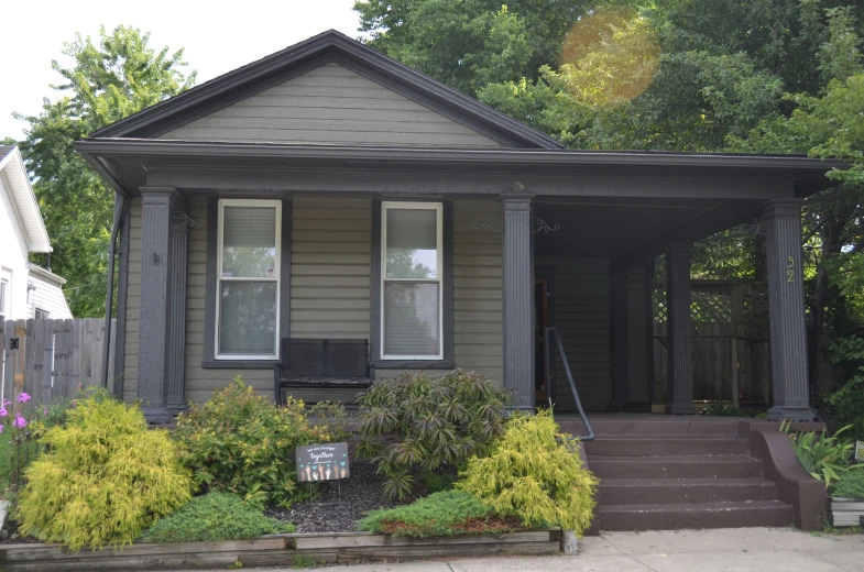 there is a gray house that is decorated with shrubs