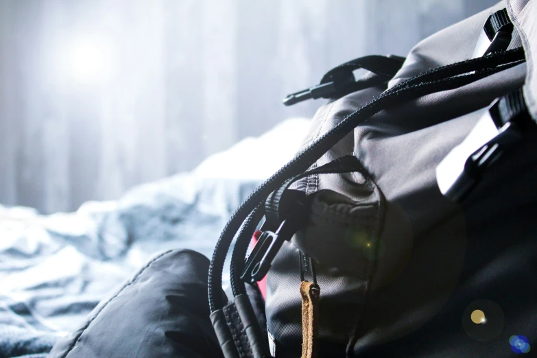 black backpack sitting on the bed with sunshine coming through it
