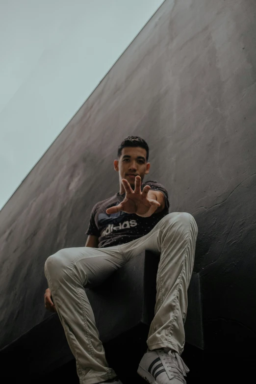 a man sitting on a wall holding his hands together to his mouth