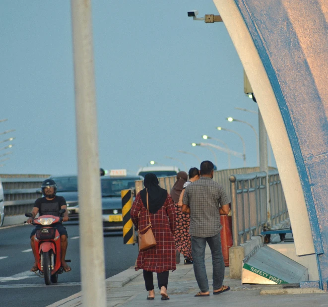 two people walk toward a parked scooter on the street