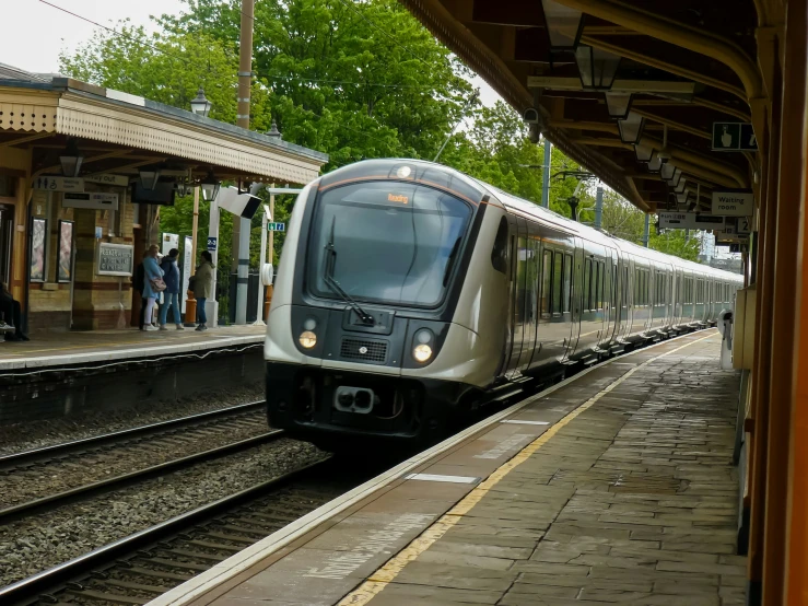 a long silver train is traveling down the track