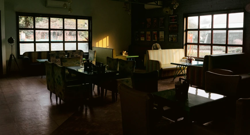 dark room with dark tables and chairs and large windows