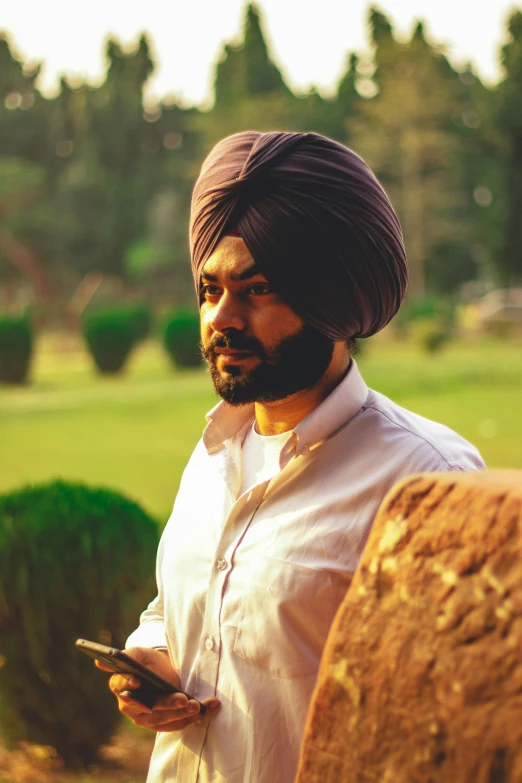 a man dressed in a turban looks at his cell phone