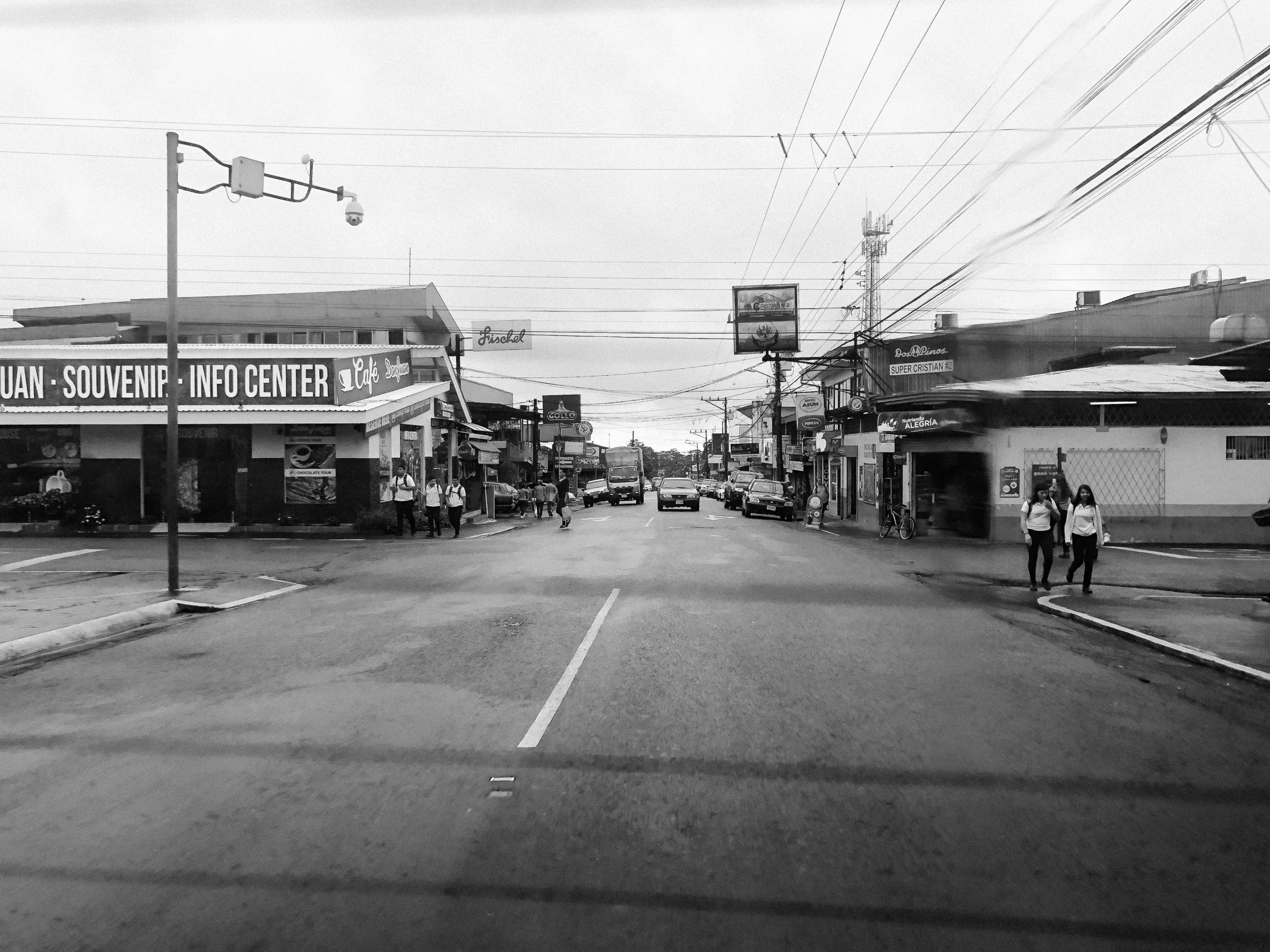 two people walking down an empty street next to shops