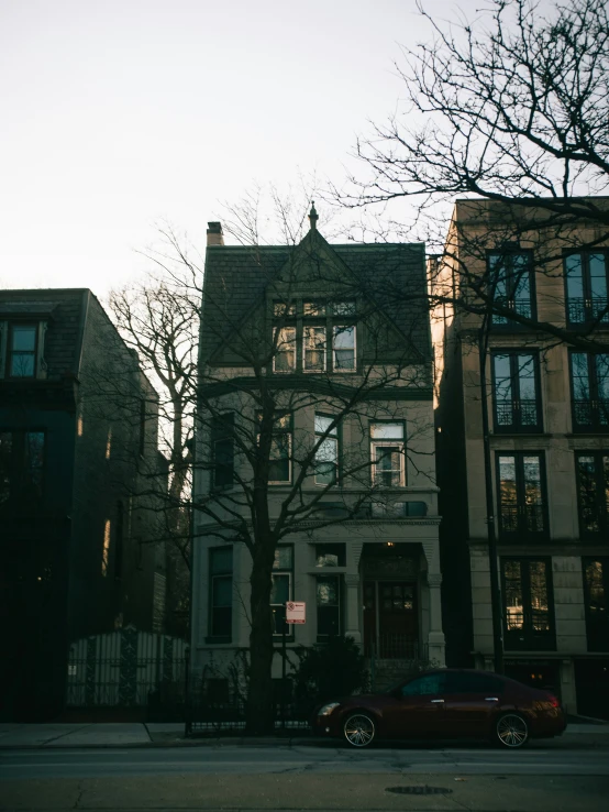 a red car parked in front of tall houses