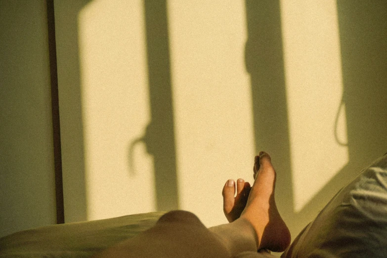 a woman's foot in a bed with the shadows cast by it