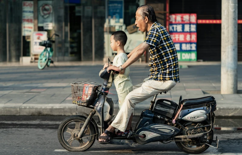 a man and boy riding on the back of a motorcycle