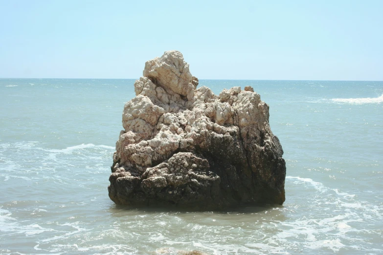 the large rock is in the middle of the ocean