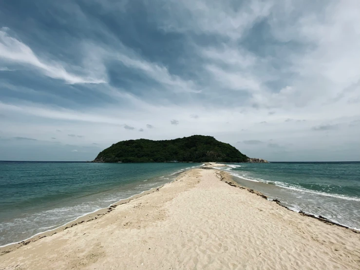 a sandy beach next to the ocean and an island in the distance