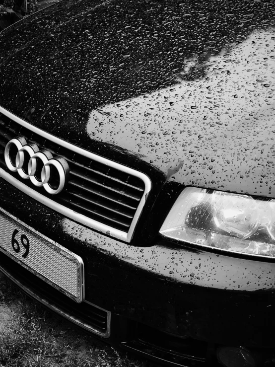 black and white po of a parked car with the rain on it