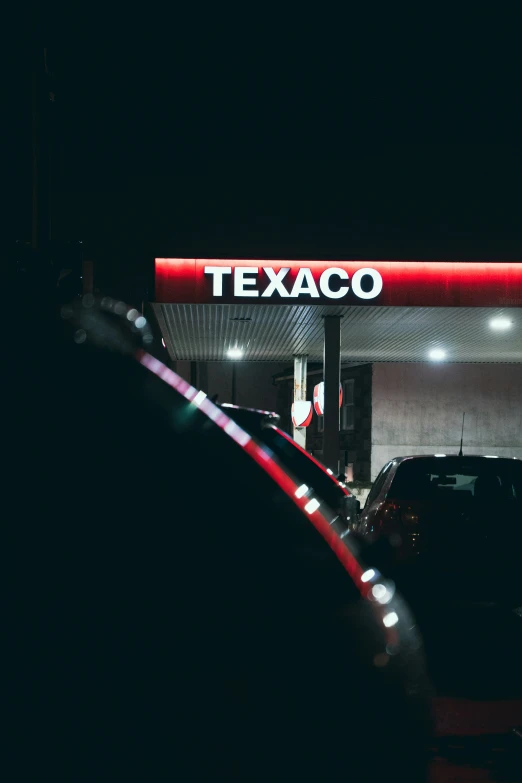 a gas station with some cars at night