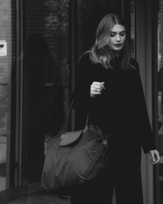 a woman is walking down a city street carrying a handbag