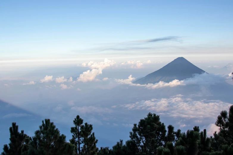 two mountains in the distance with clouds and trees below