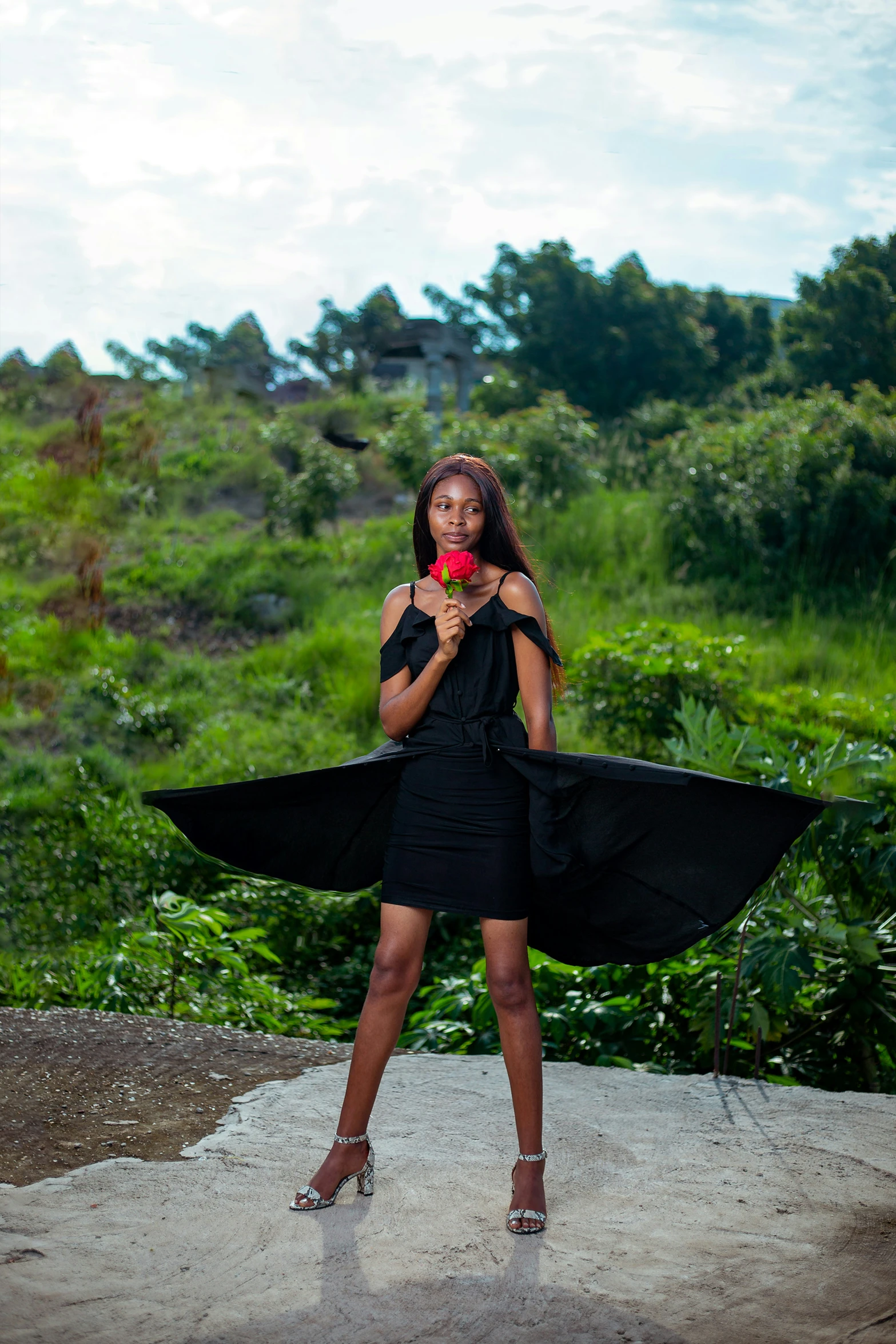 a woman posing in black dress and black cape