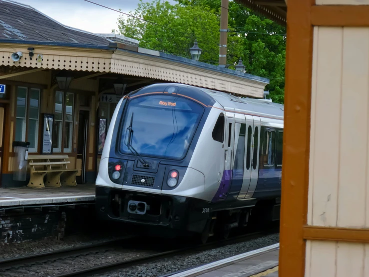 a silver and purple train parked at a train station