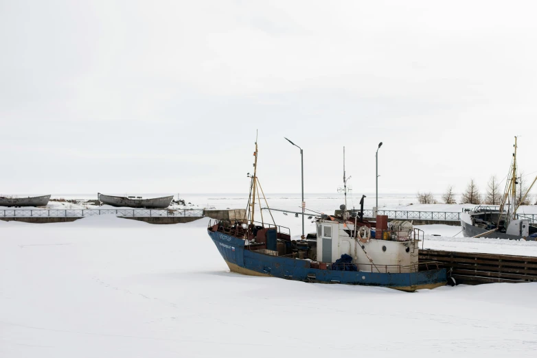 two boats in the water sitting on a snowy surface